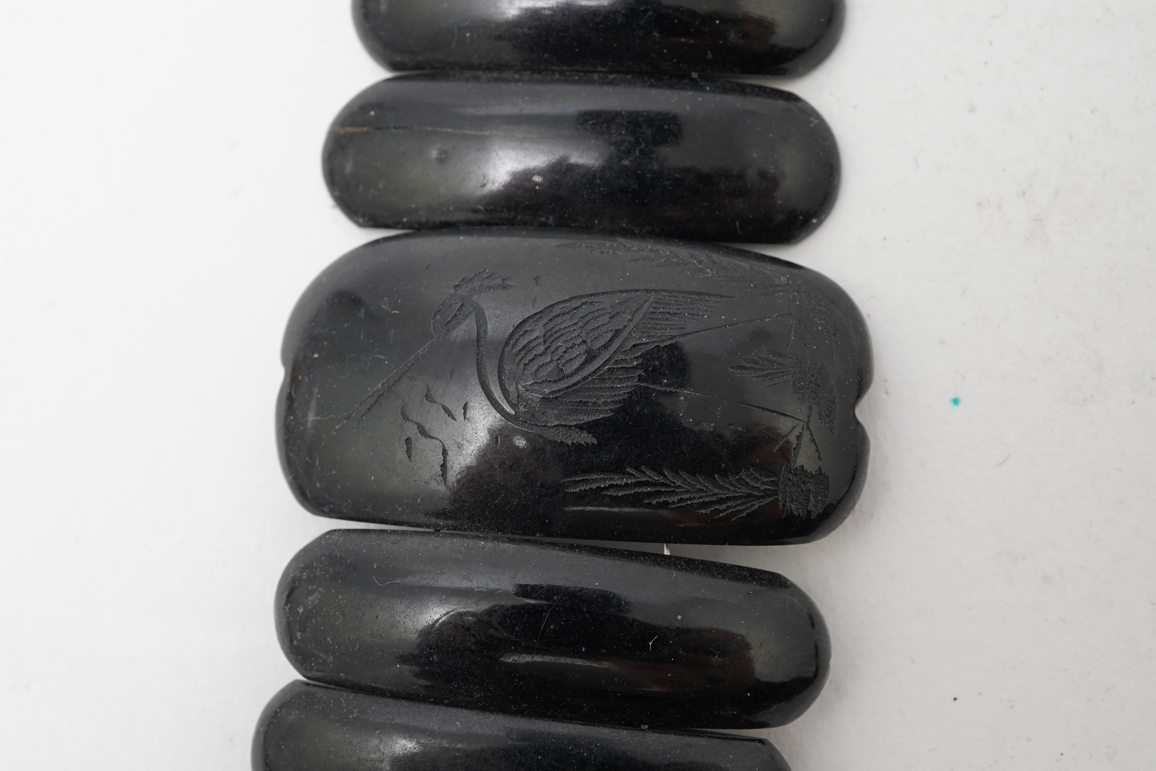 A collection of jewels, comprising: a moulded bog oak brooch depicting a hand holding a posy, length 7.4cm; a carved jet brooch depicting a Gothic ruin, possibly part of Whitby Abbey; a necklace composed of polished pane